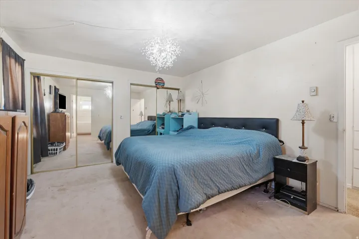Bedroom featuring multiple closets, light carpet, and hanging lights
