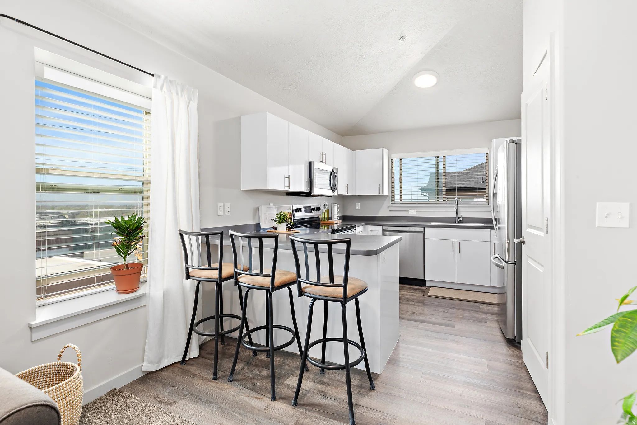 Kitchen featuring white cabinetry, lofted ceiling, a peninsula, stainless steel appliances, and a breakfast bar area and Lake Views. Refrigerator stays!