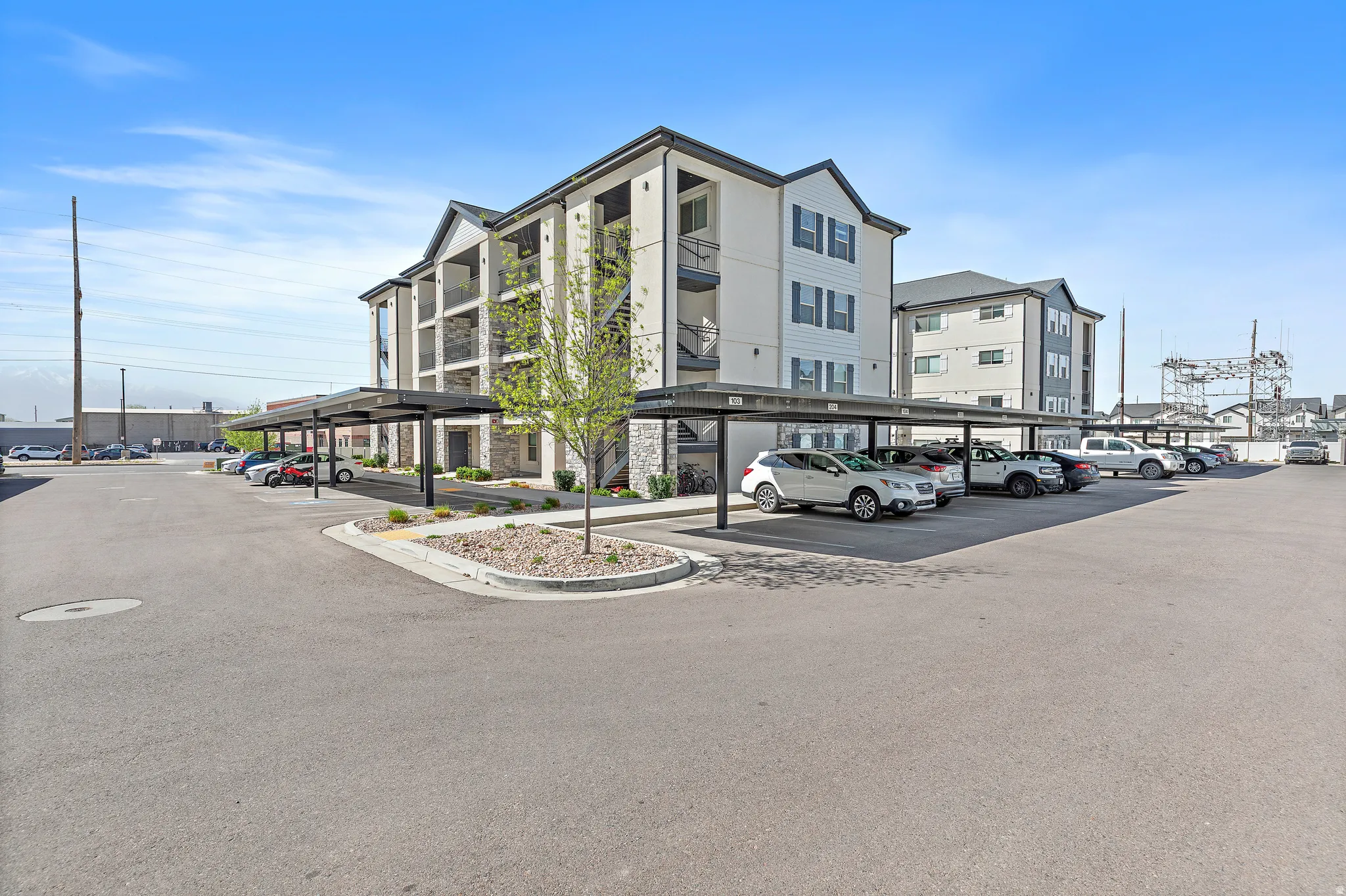 View of apartment building / complex featuring covered parking