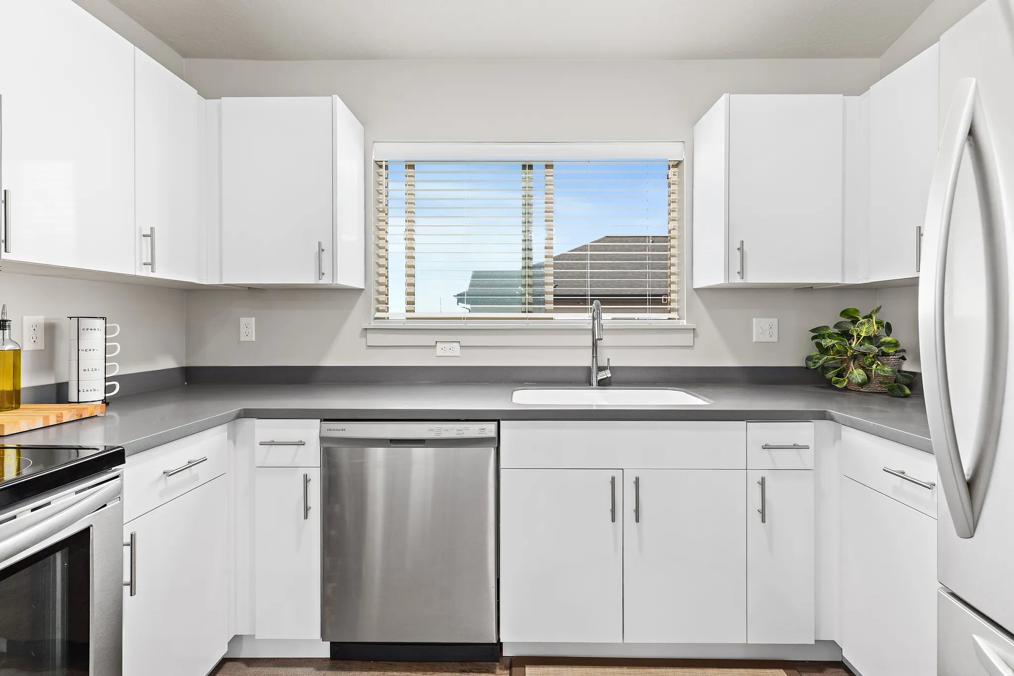 Kitchen with stainless steel appliances, white cabinetry, and dark countertops