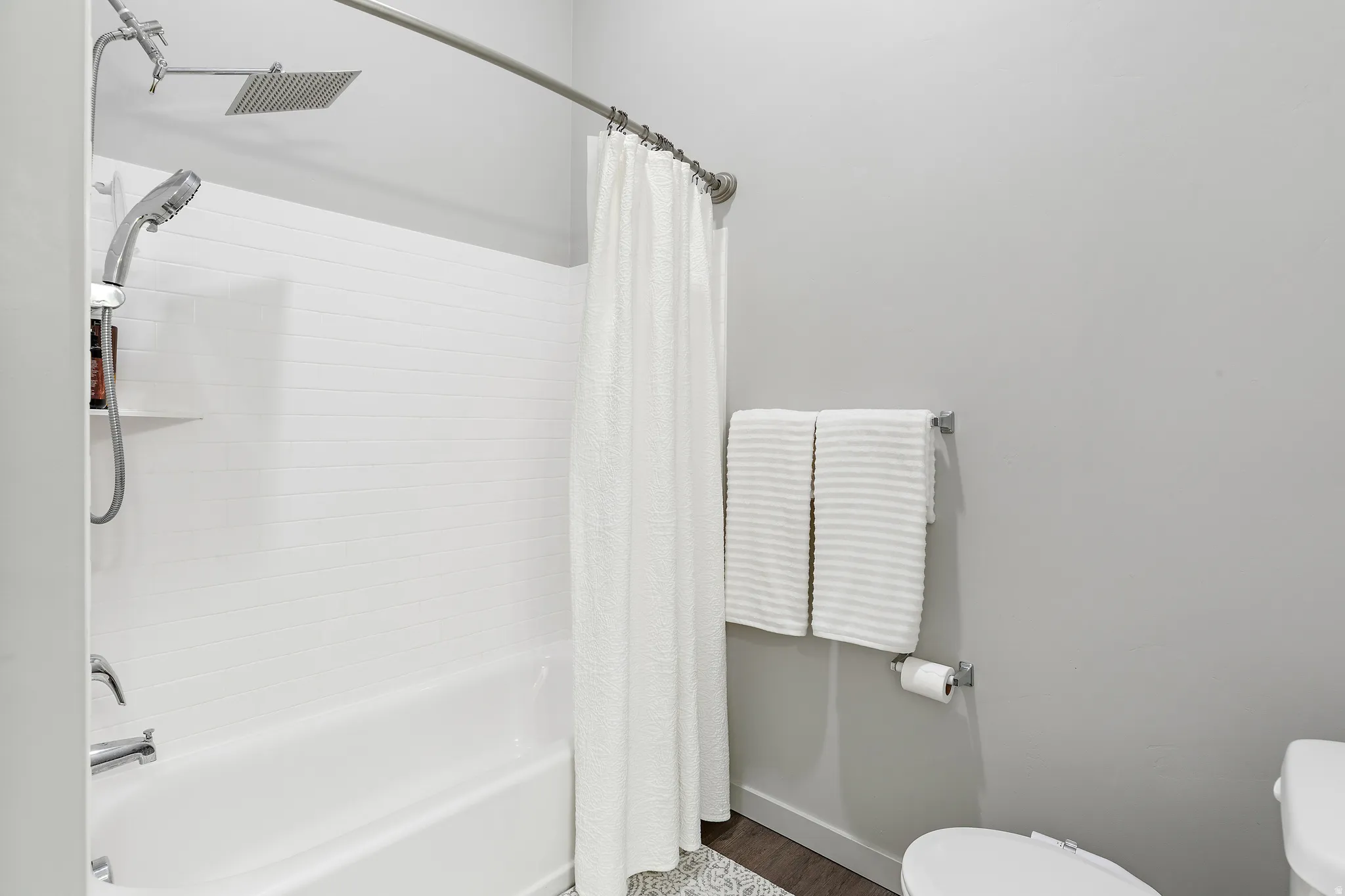 Full bathroom with toilet and shower / tub combo with curtain