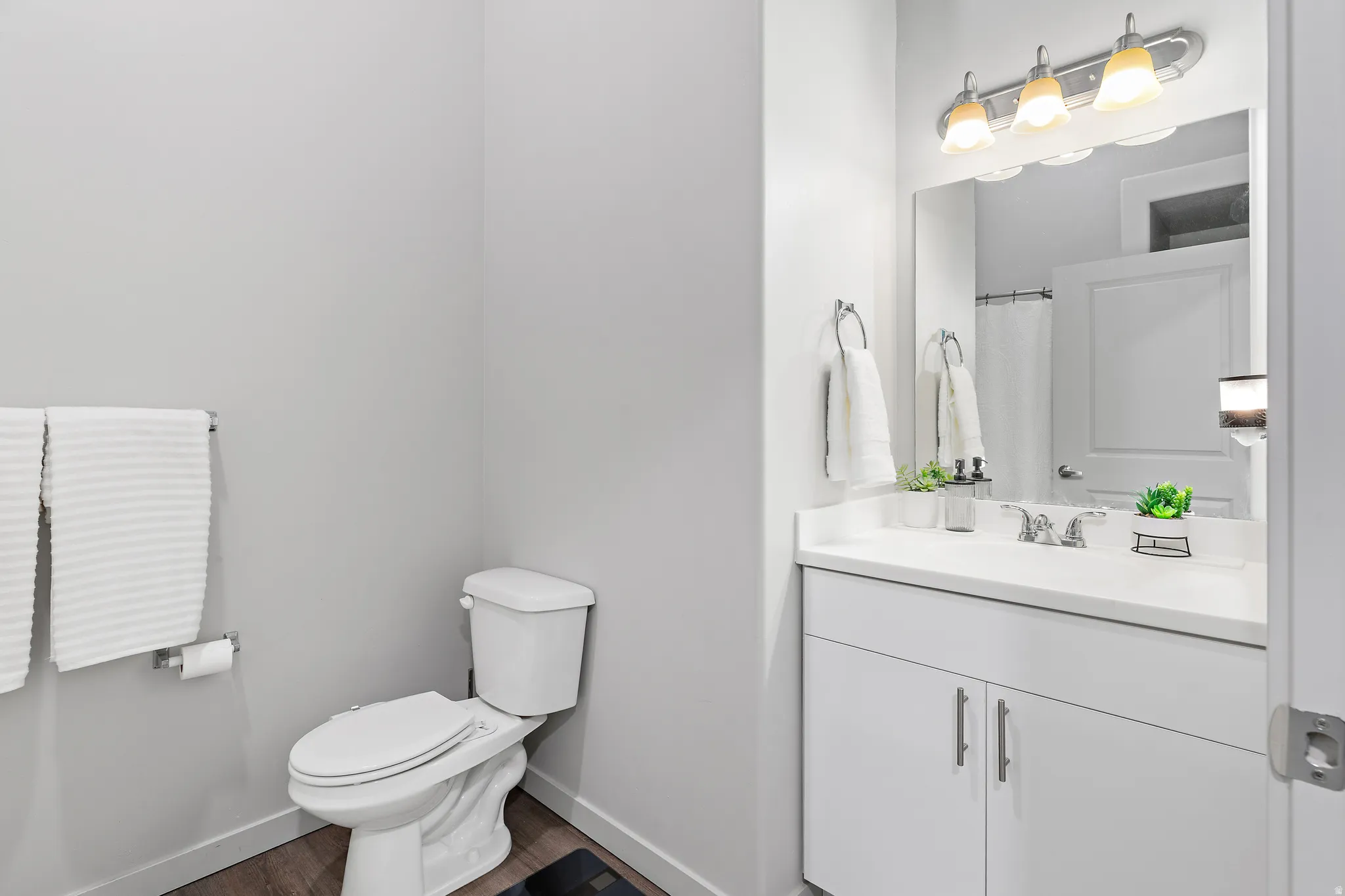 Full bathroom with vanity, a shower with shower curtain, and dark wood-style floors