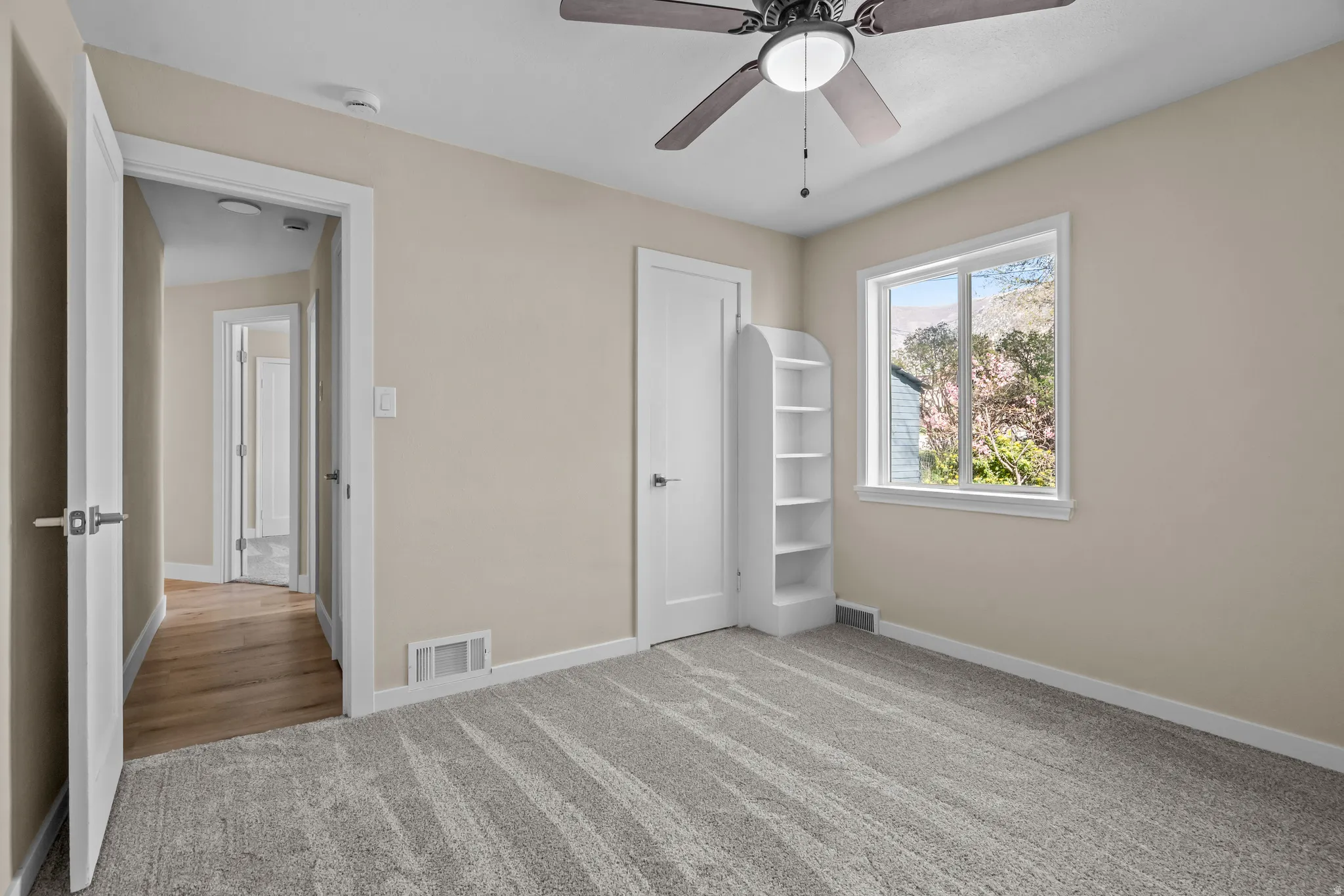 Unfurnished bedroom with light colored carpet, a ceiling fan, and a closet