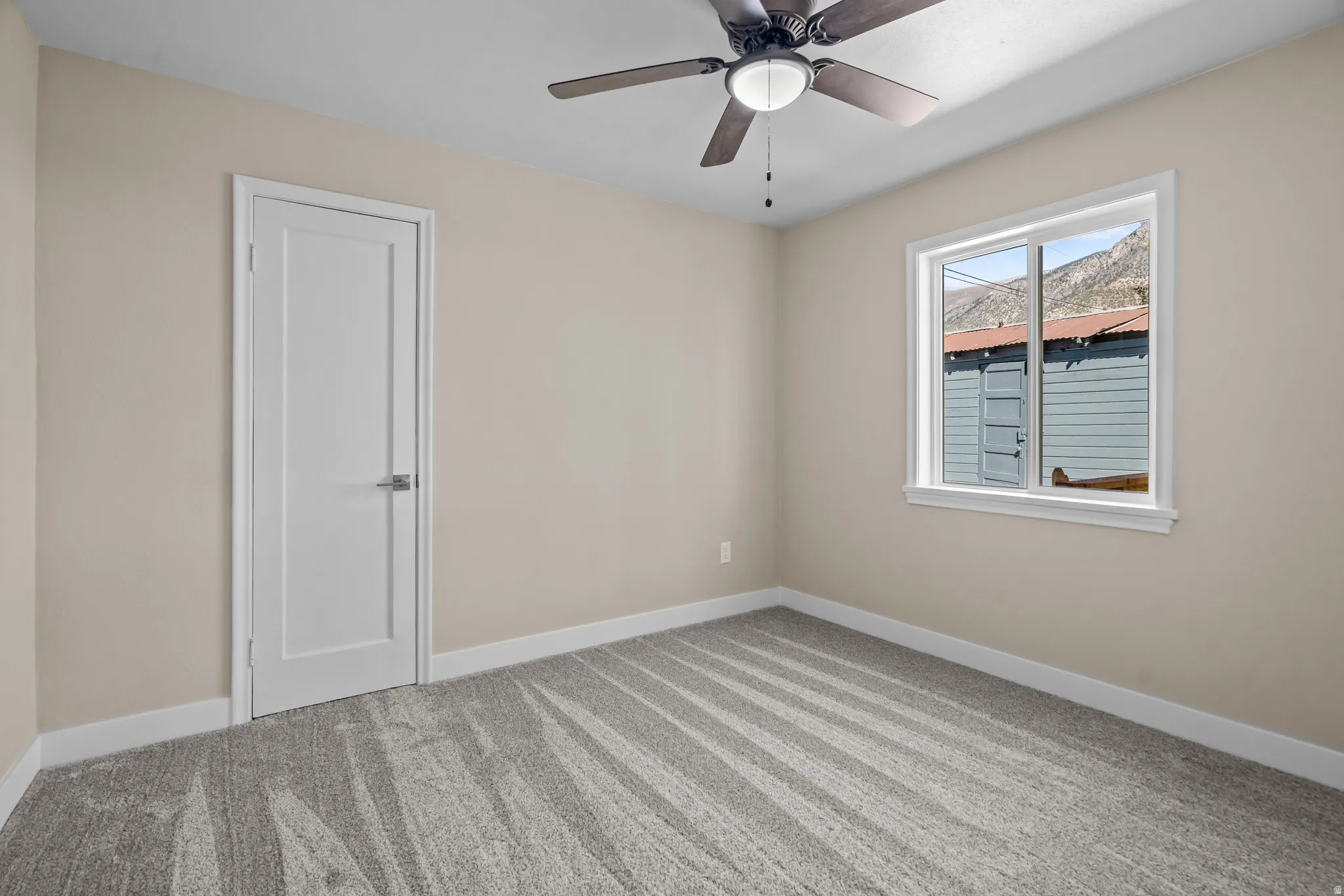 Spare room featuring light carpet and ceiling fan