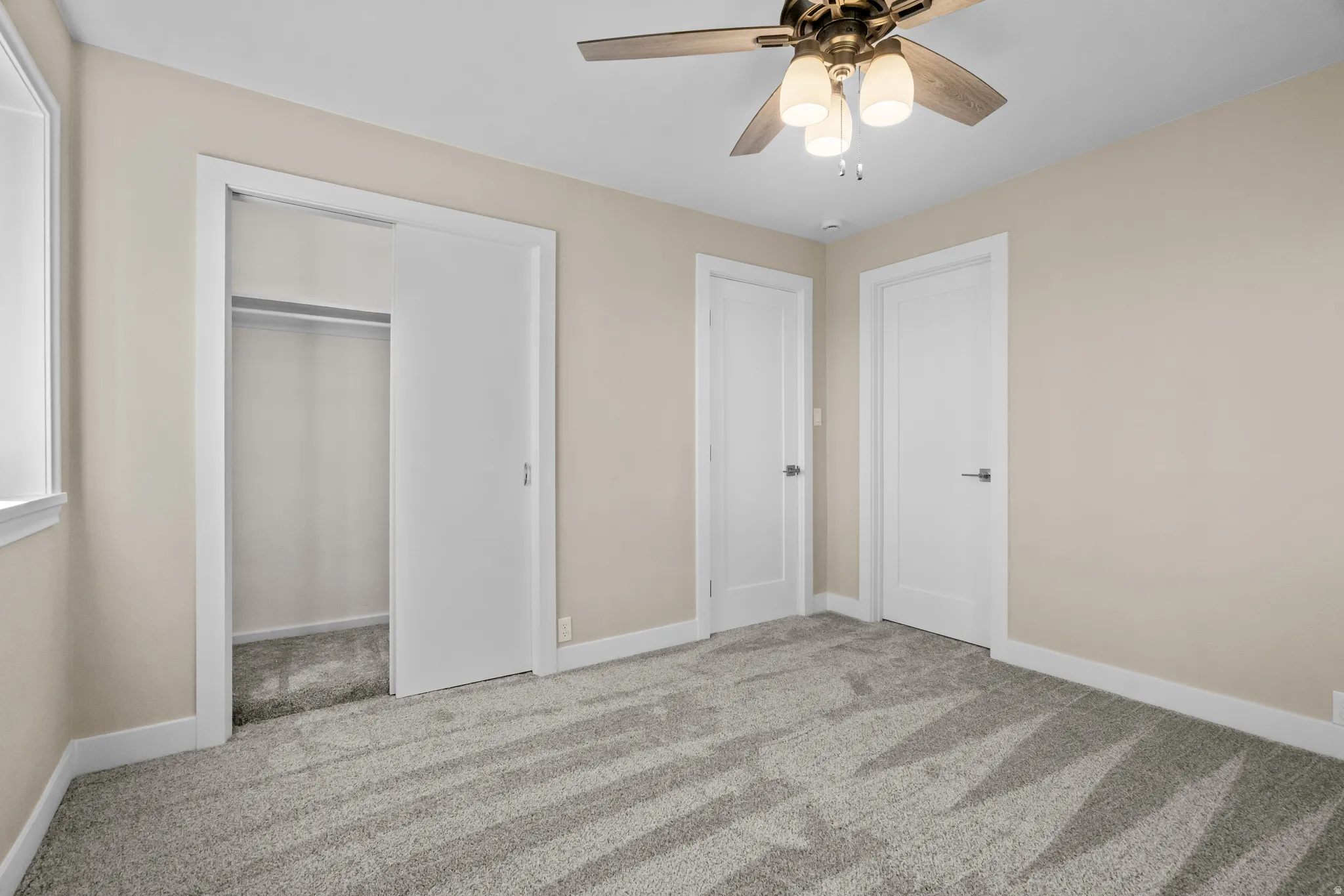 Unfurnished bedroom featuring light colored carpet, a closet, and a ceiling fan