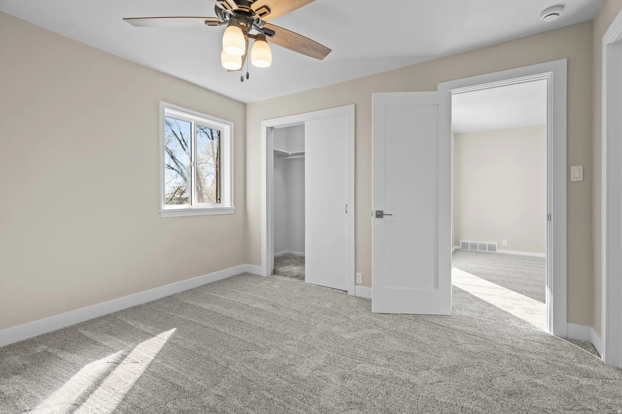 Unfurnished bedroom with light colored carpet and a ceiling fan