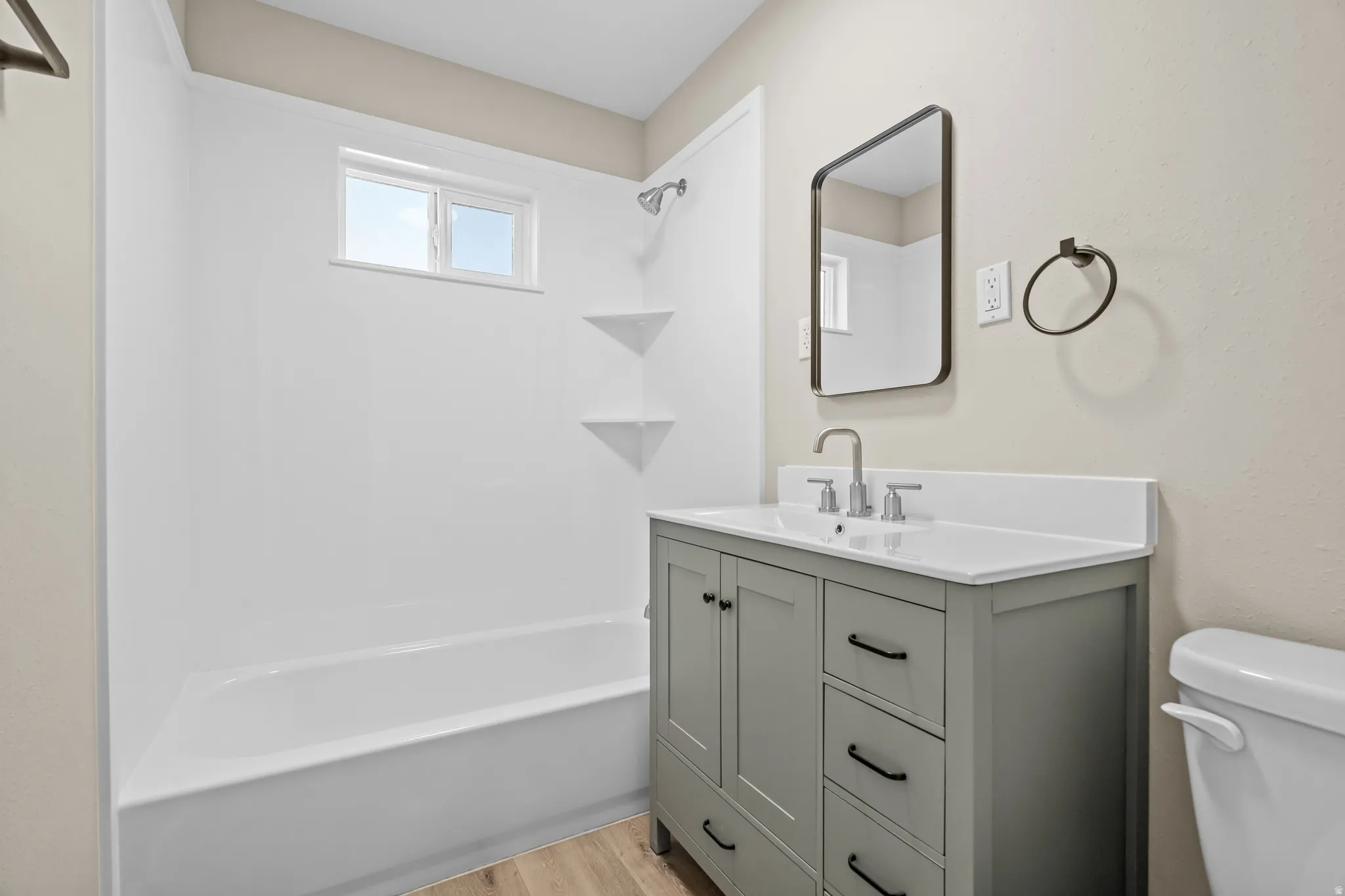 Full bathroom with vanity, washtub / shower combination, and light wood-style flooring
