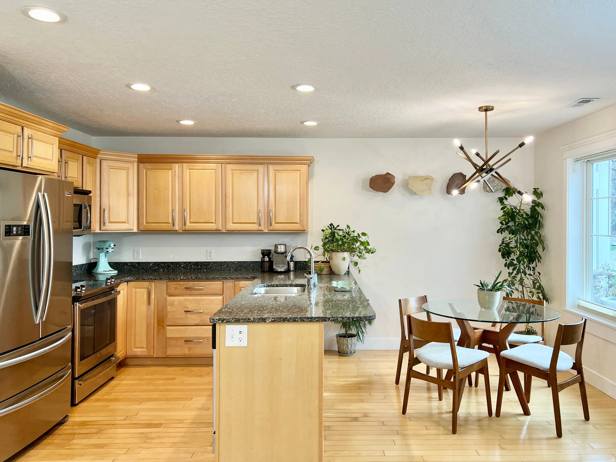 Kitchen with a peninsula, stainless steel appliances, dark stone countertops, a kitchen bar, and light wood-style flooring