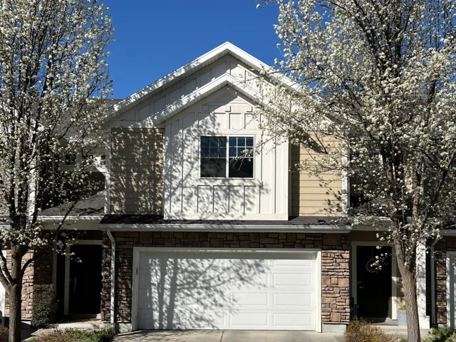 View of front of home with stone siding, an attached garage, and concrete driveway