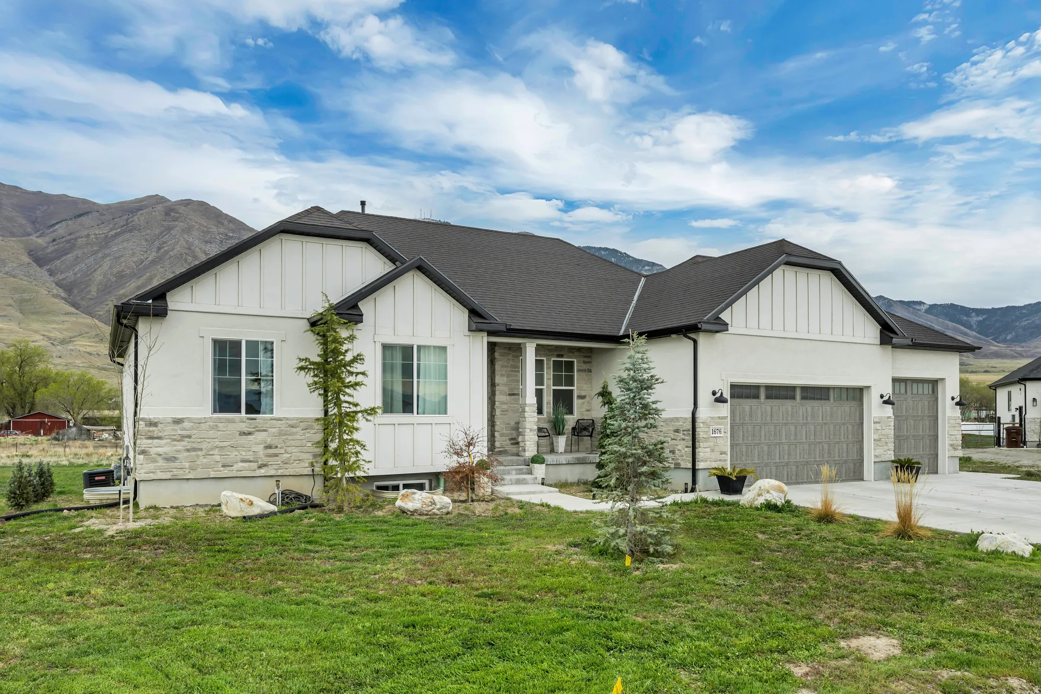 Modern farmhouse style home featuring board and batten siding, a mountain view, a front yard, and an attached garage