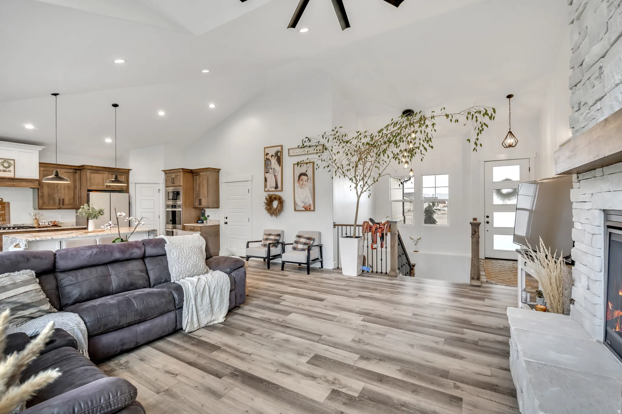 Living room featuring a fireplace, light wood-type flooring, recessed lighting, lofted ceiling, and ceiling fan
