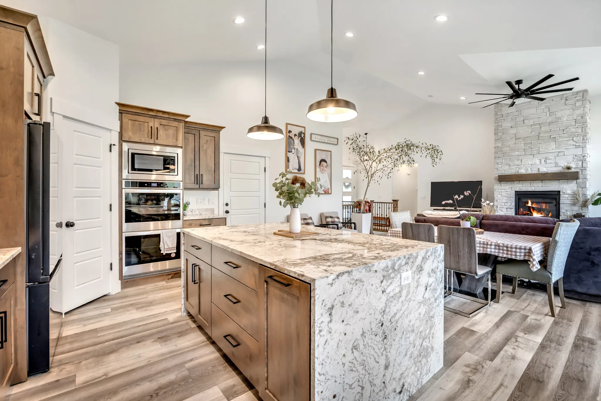 Kitchen featuring light stone countertops, a kitchen island, open floor plan, lofted ceiling, and stainless steel appliances