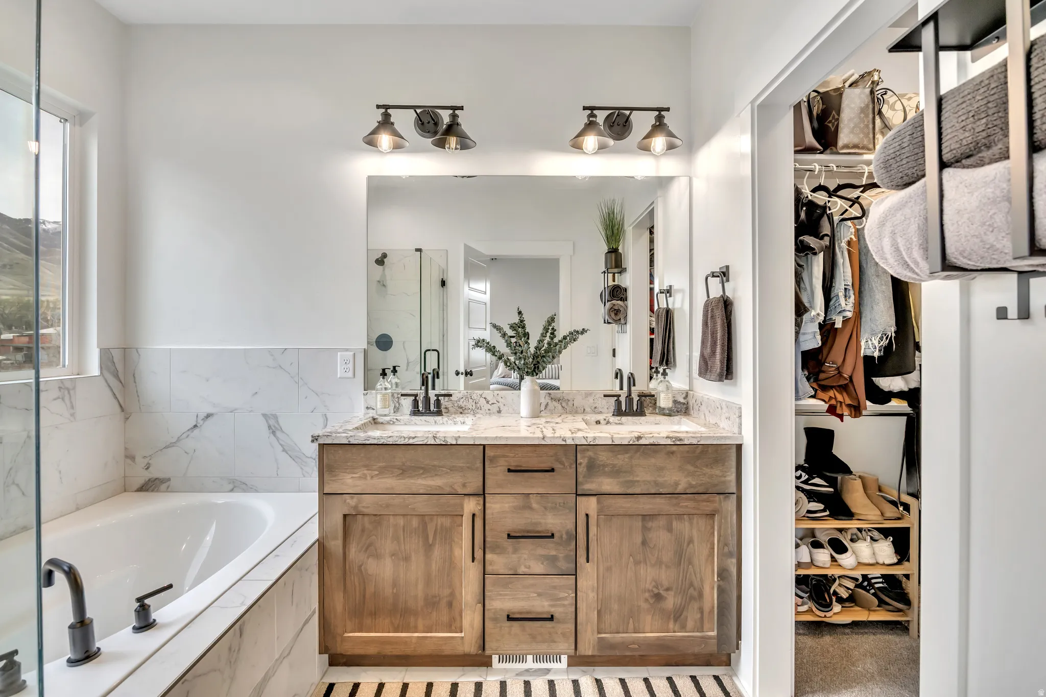 Bathroom with double vanity, a walk in closet, a marble finish shower, and a garden tub