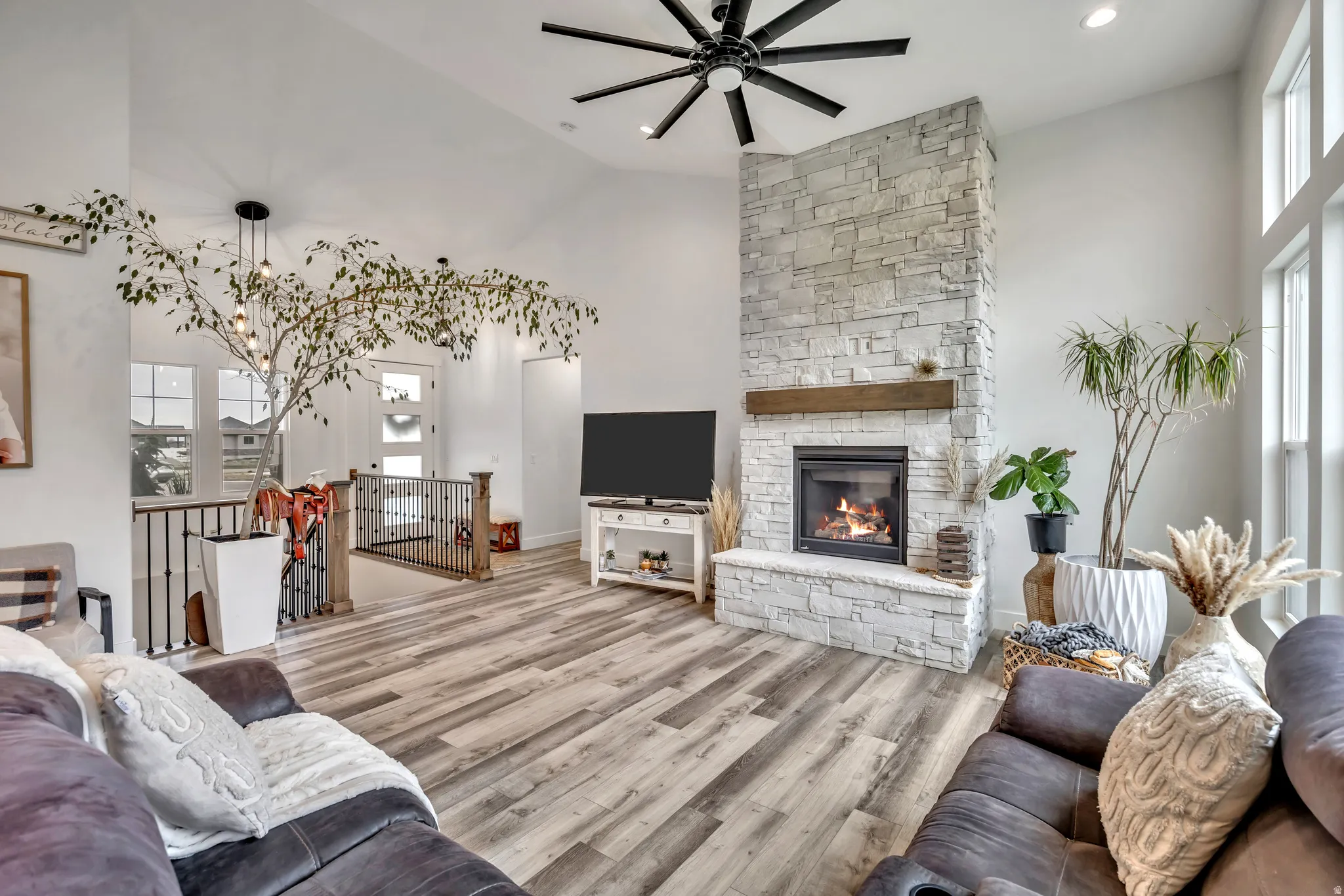 Living area with light wood-type flooring, a fireplace, a ceiling fan, vaulted ceiling, and recessed lighting