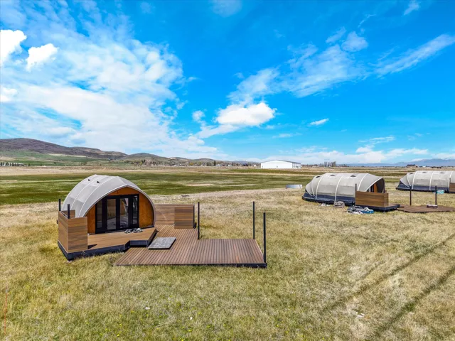 View of green lawn with a view of rural / pastoral area, a deck with mountain view, and an outbuilding