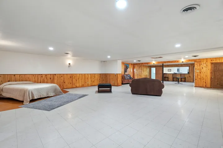Bedroom with wooden walls, light floors, wainscoting, and recessed lighting