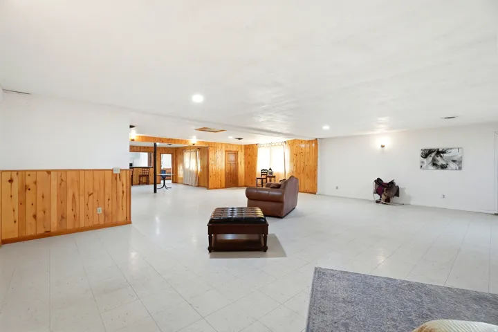Living room featuring wooden walls, light floors, and a wainscoted wall