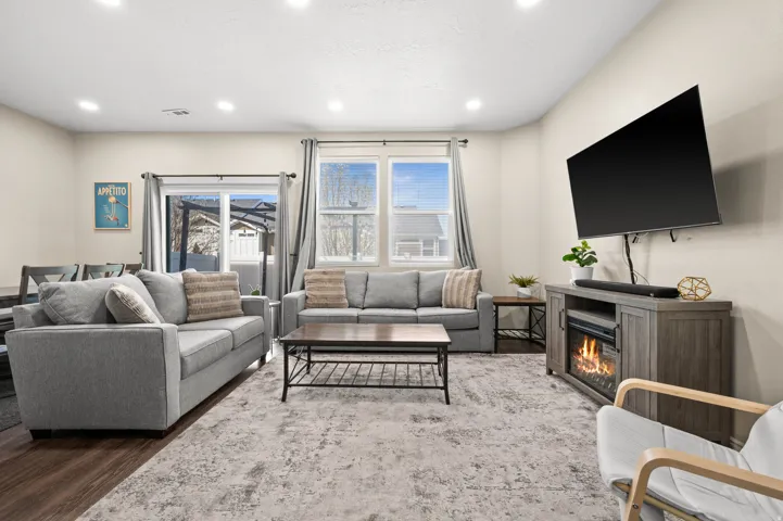 Living room with wood finished floors, a glass covered fireplace, and recessed lighting