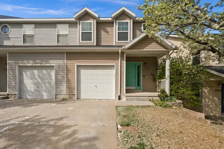 View of front of property with covered porch, an attached garage, and driveway