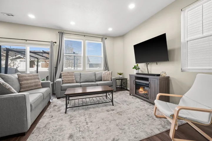 Living room with wood finished floors, healthy amount of natural light, recessed lighting, and a glass covered fireplace
