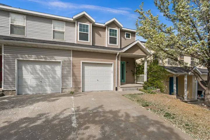 Traditional home featuring an attached garage, driveway, and covered porch