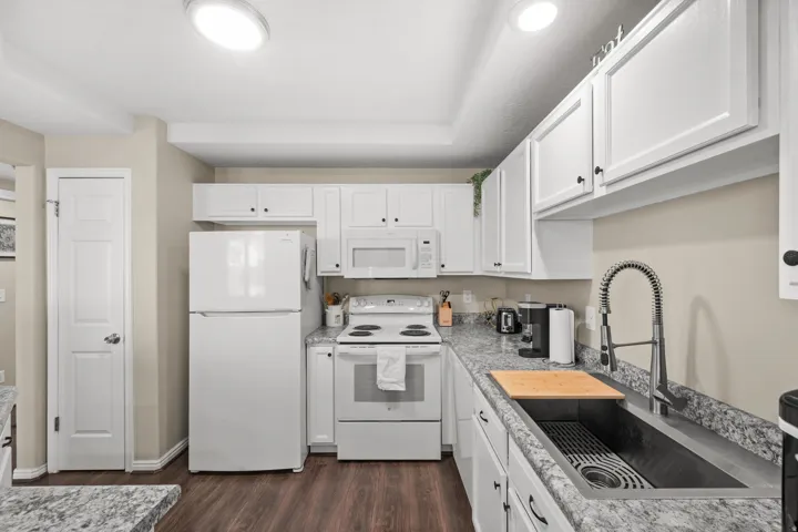 Kitchen featuring white appliances, white cabinetry, and dark wood-style flooring