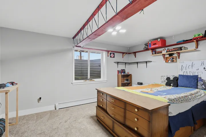Bedroom featuring light carpet and baseboard heating