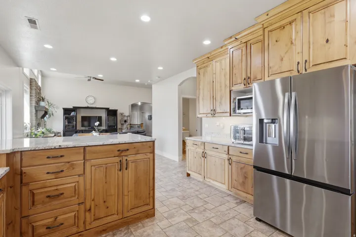 Kitchen featuring stainless steel appliances, light stone counters, arched walkways, open floor plan, and recessed lighting