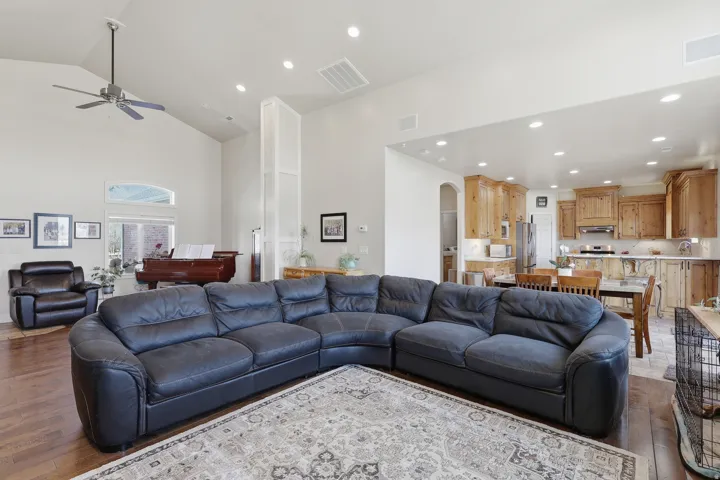 Living room featuring dark wood-type flooring, arched walkways, a ceiling fan, vaulted ceiling, and recessed lighting