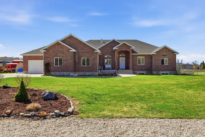Ranch-style house with brick siding, a garage, a front yard, driveway, and a shingled roof