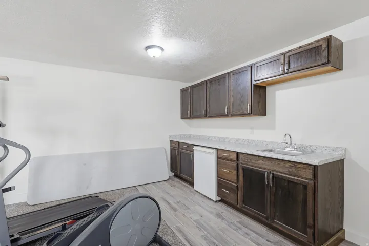 Kitchen featuring a textured ceiling, dark wood finish cabinets, light countertops, and light wood-style floors