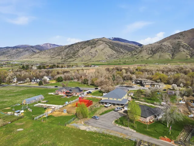 Aerial view of property and surrounding area featuring a mountainous background and nearby suburban area
