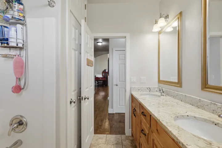 Full bath with double vanity, light wood finished floors, and washtub / shower combination