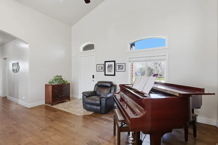 Sitting room featuring arched walkways, hardwood / wood-style flooring, vaulted ceiling, and a ceiling fan