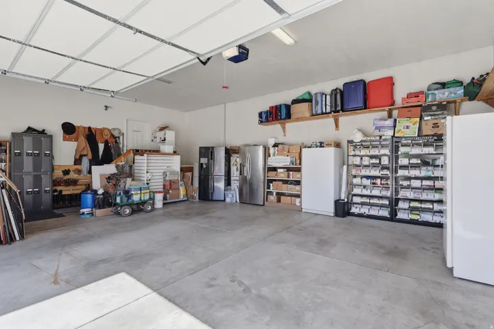 Garage with freestanding refrigerator, stainless steel refrigerator with ice dispenser, and a garage door opener
