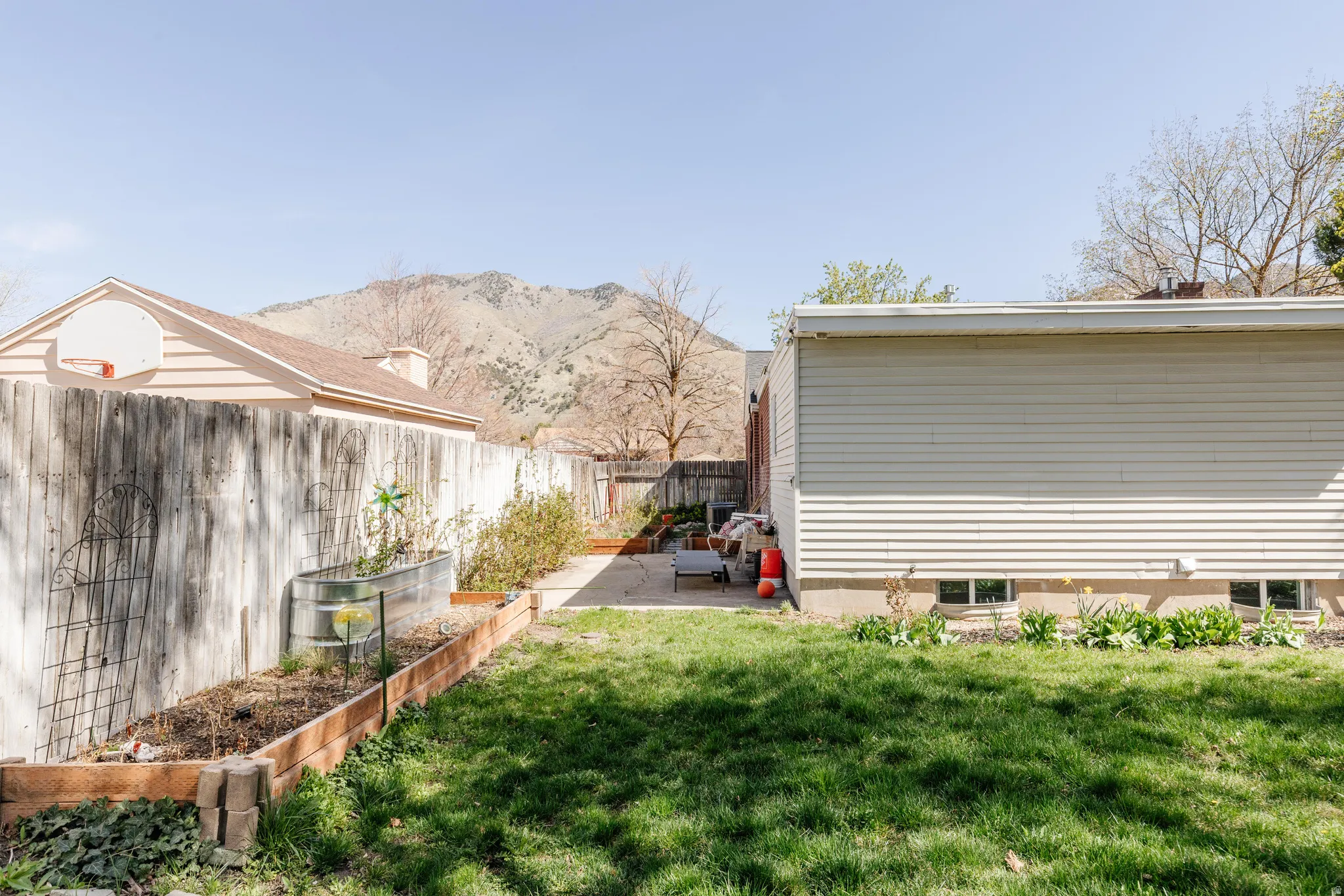 Fenced backyard featuring a patio, a mountain view, and a garden