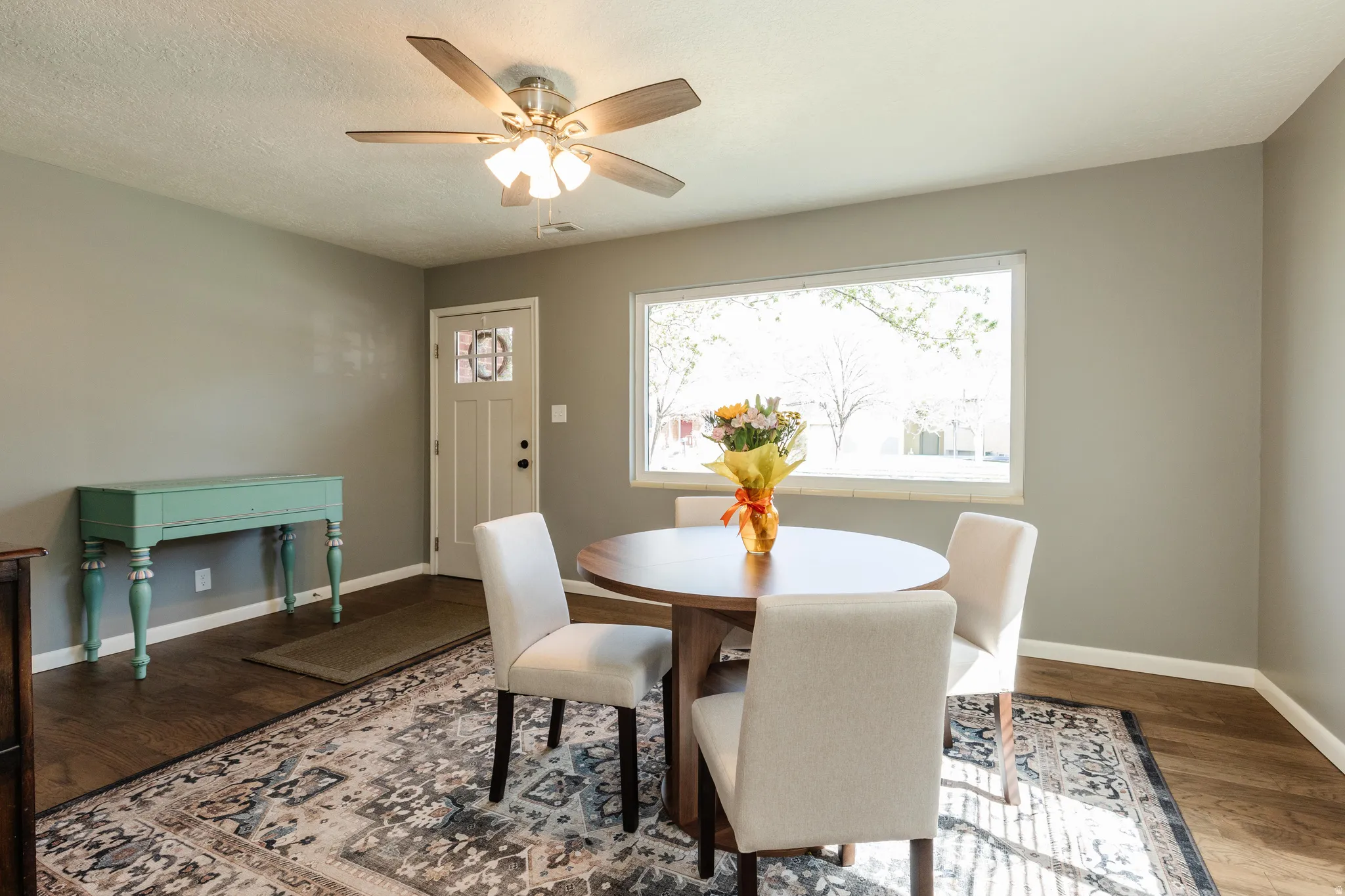 Dining space featuring wood finished floors, a ceiling fan, and a textured ceiling