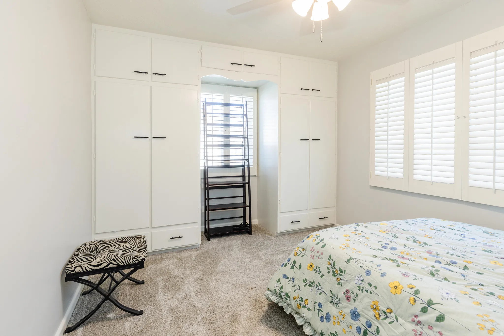 Bedroom 1 with light carpet, two closets, and a ceiling fan