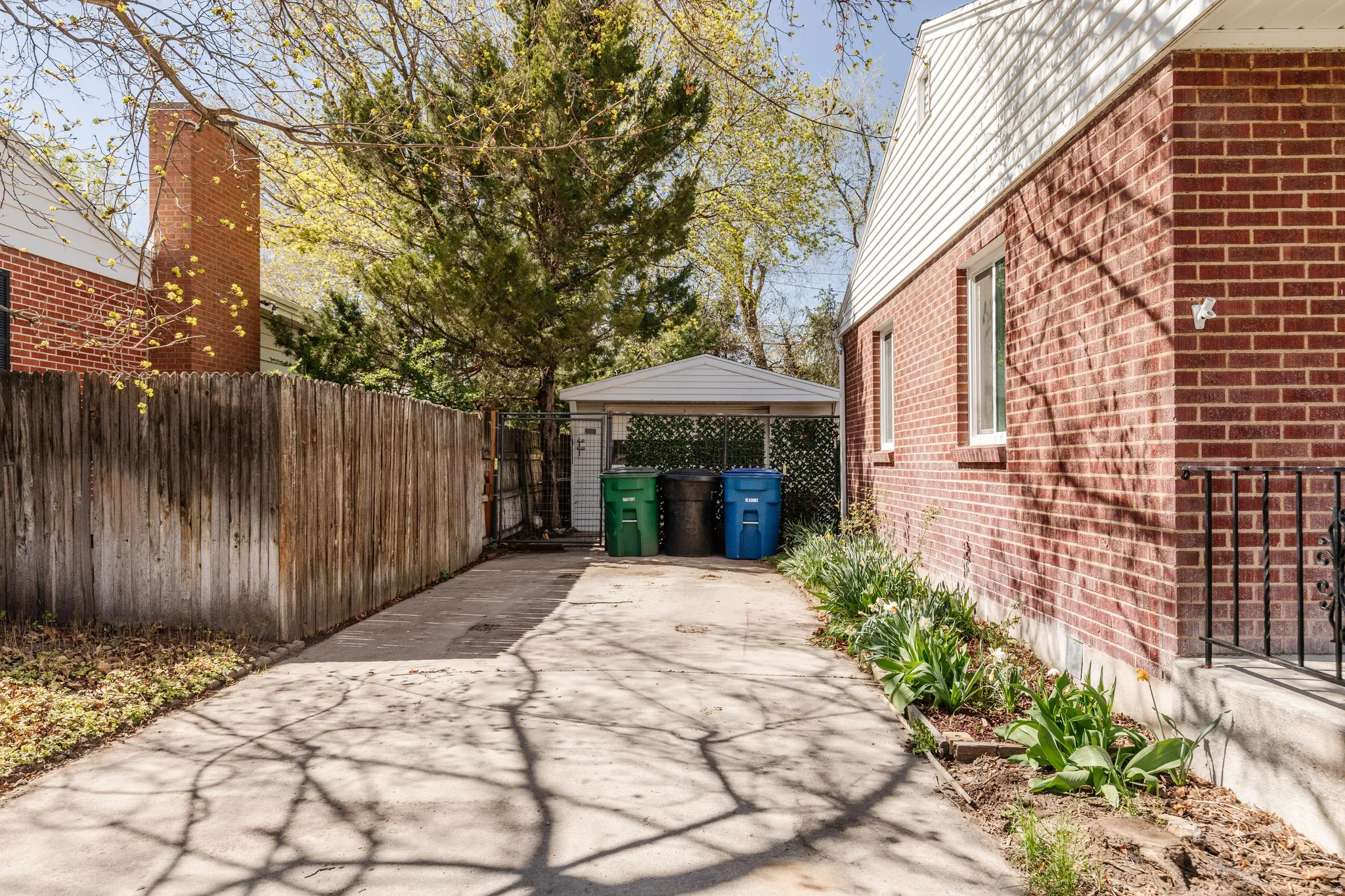 View of property driveway featuring brick siding, a gate, driveway, and a detached garage