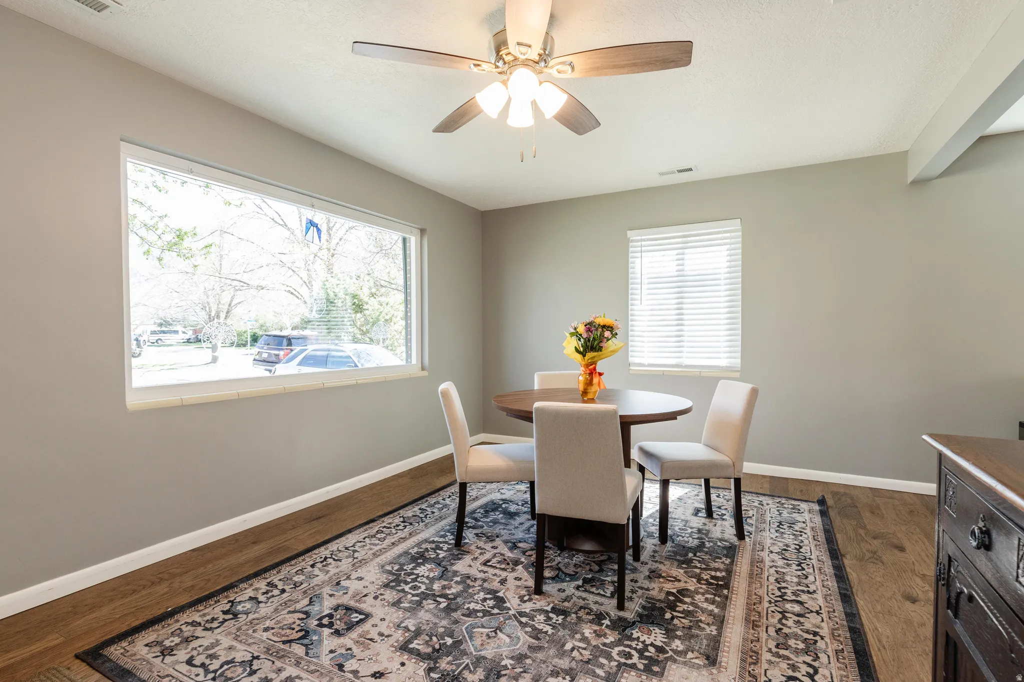 Dining space with ceiling fan and darker flooring