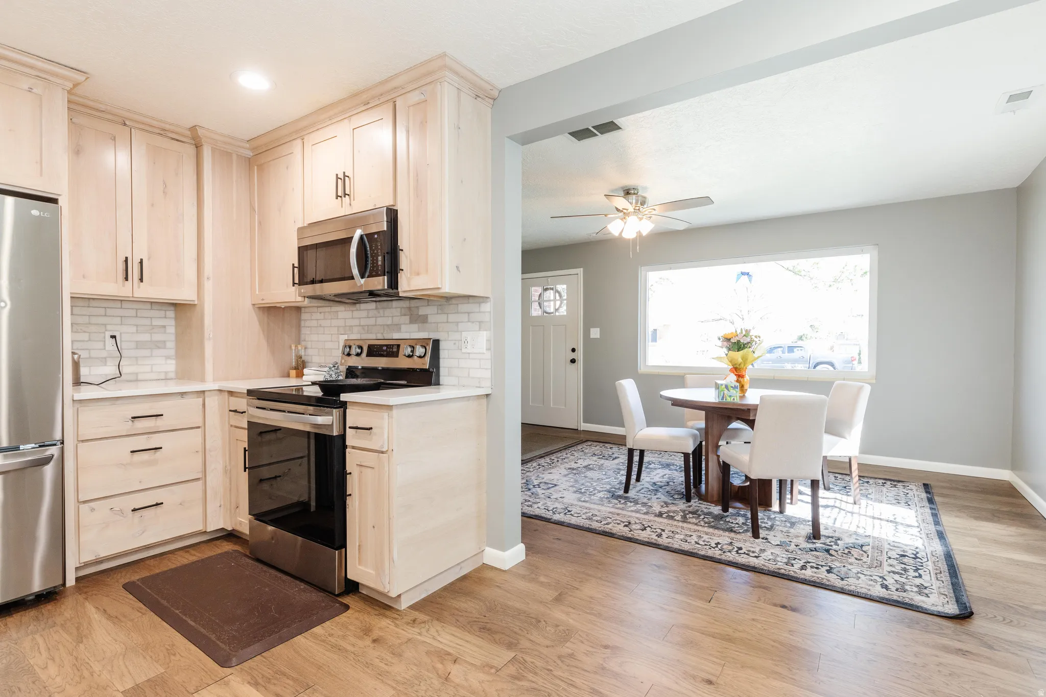 Kitchen featuring stainless steel appliances, light wood-style cabinets, light stone counters, and recessed lighting