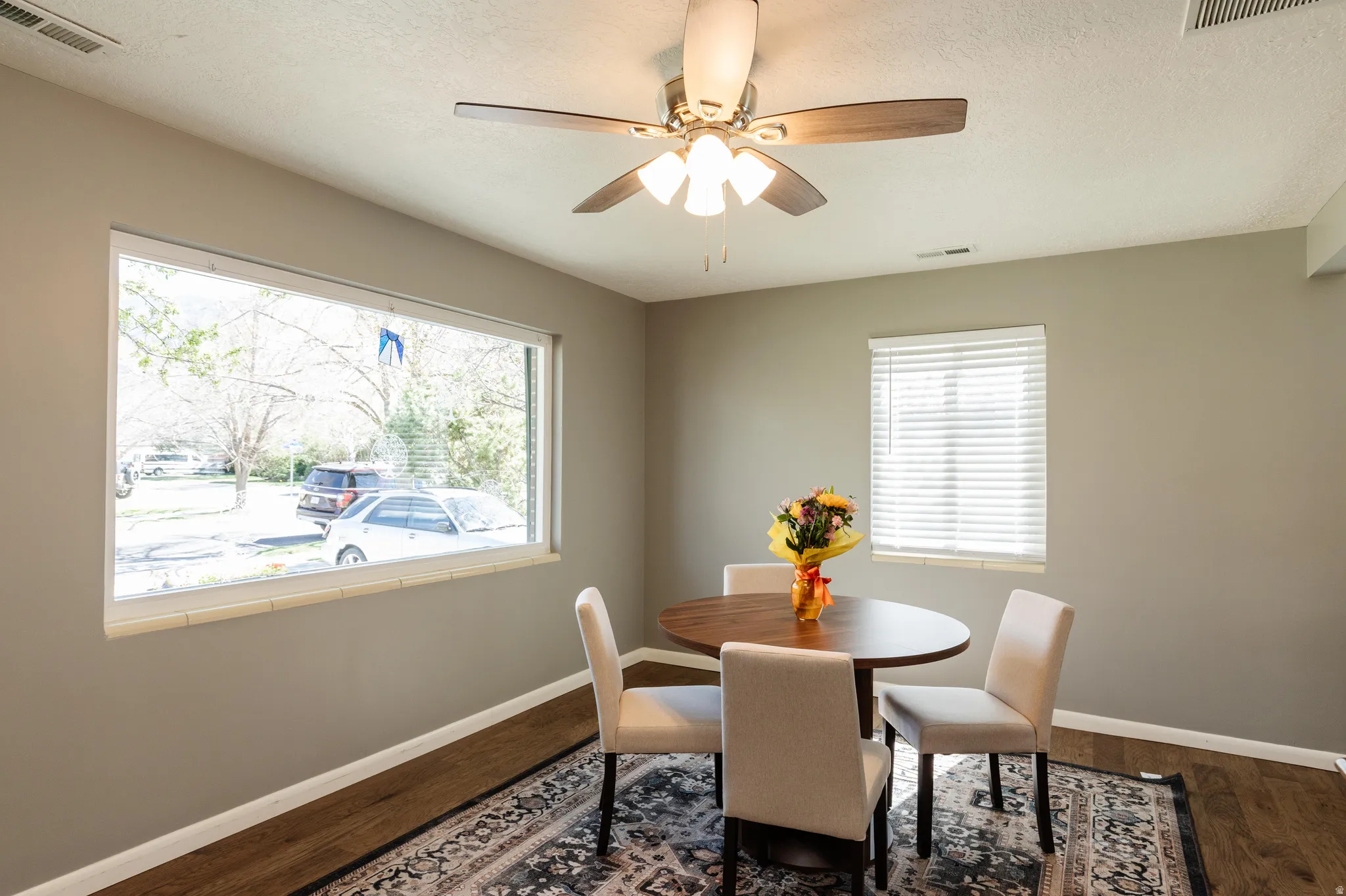 Dining room featuring ceiling fan, darker colored finished floors, and a textured ceiling