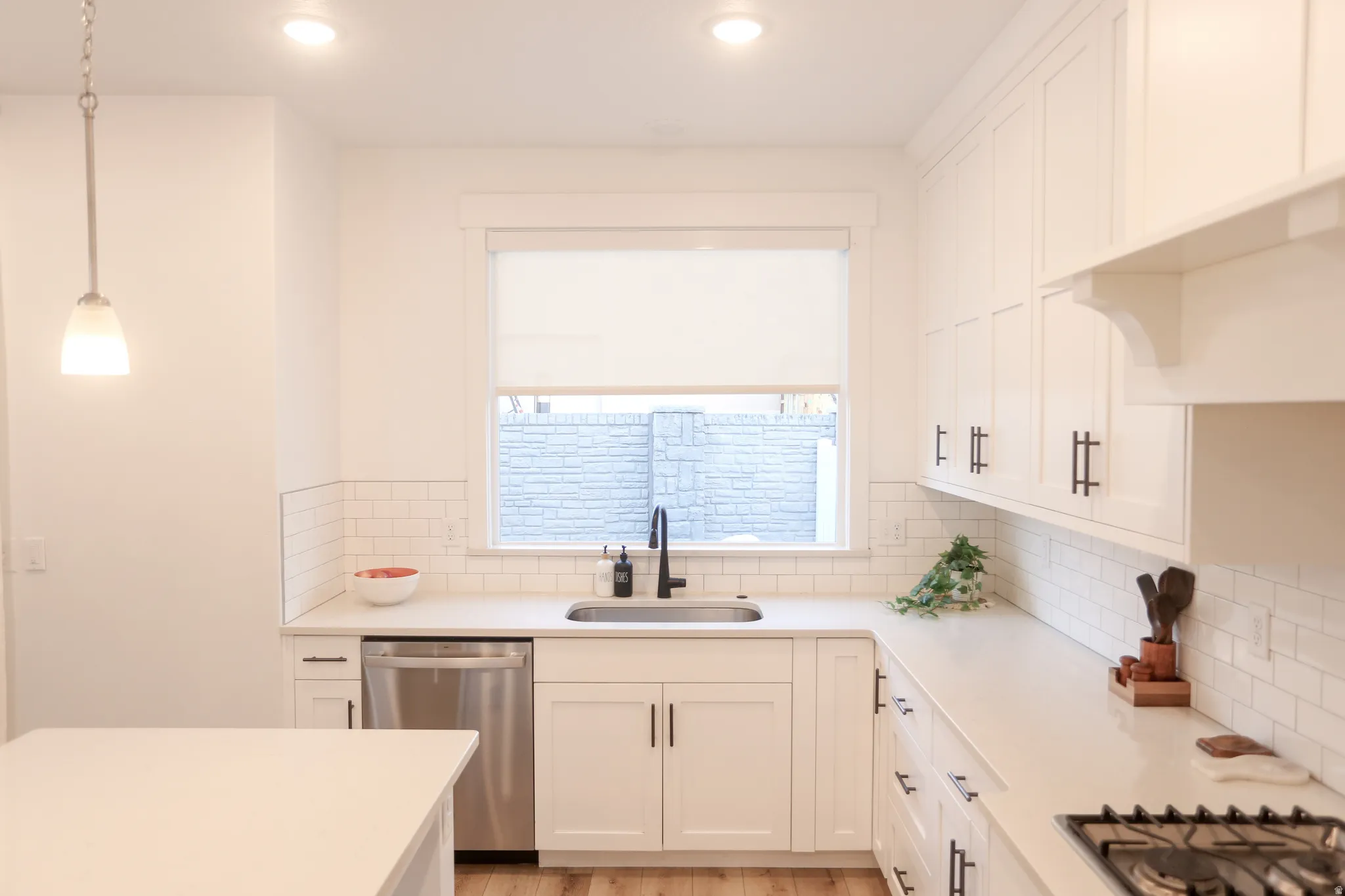Kitchen with white cabinets, stainless steel appliances, light wood-type flooring, and light stone countertops
