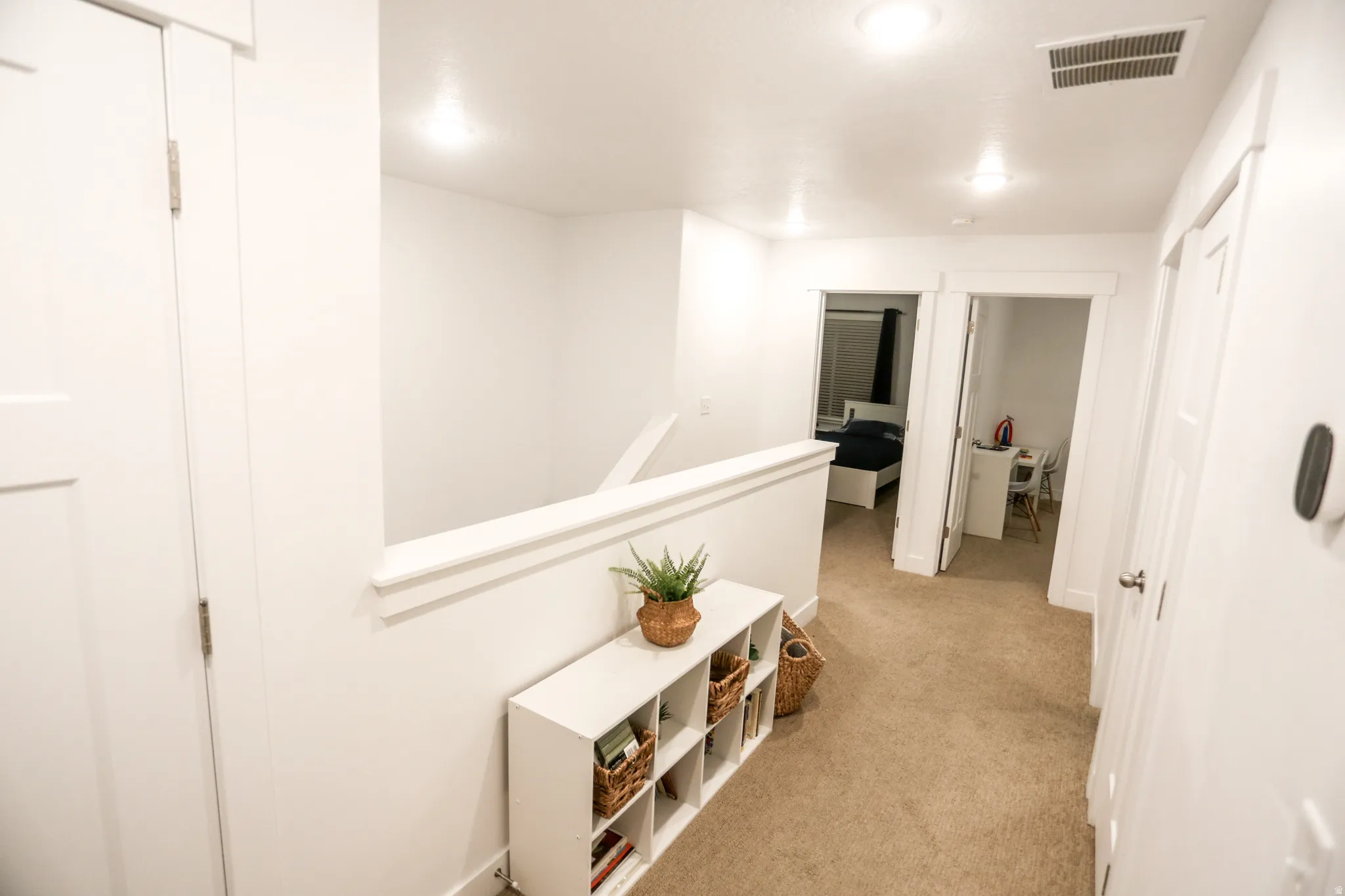 Hallway featuring an upstairs landing and light colored carpet