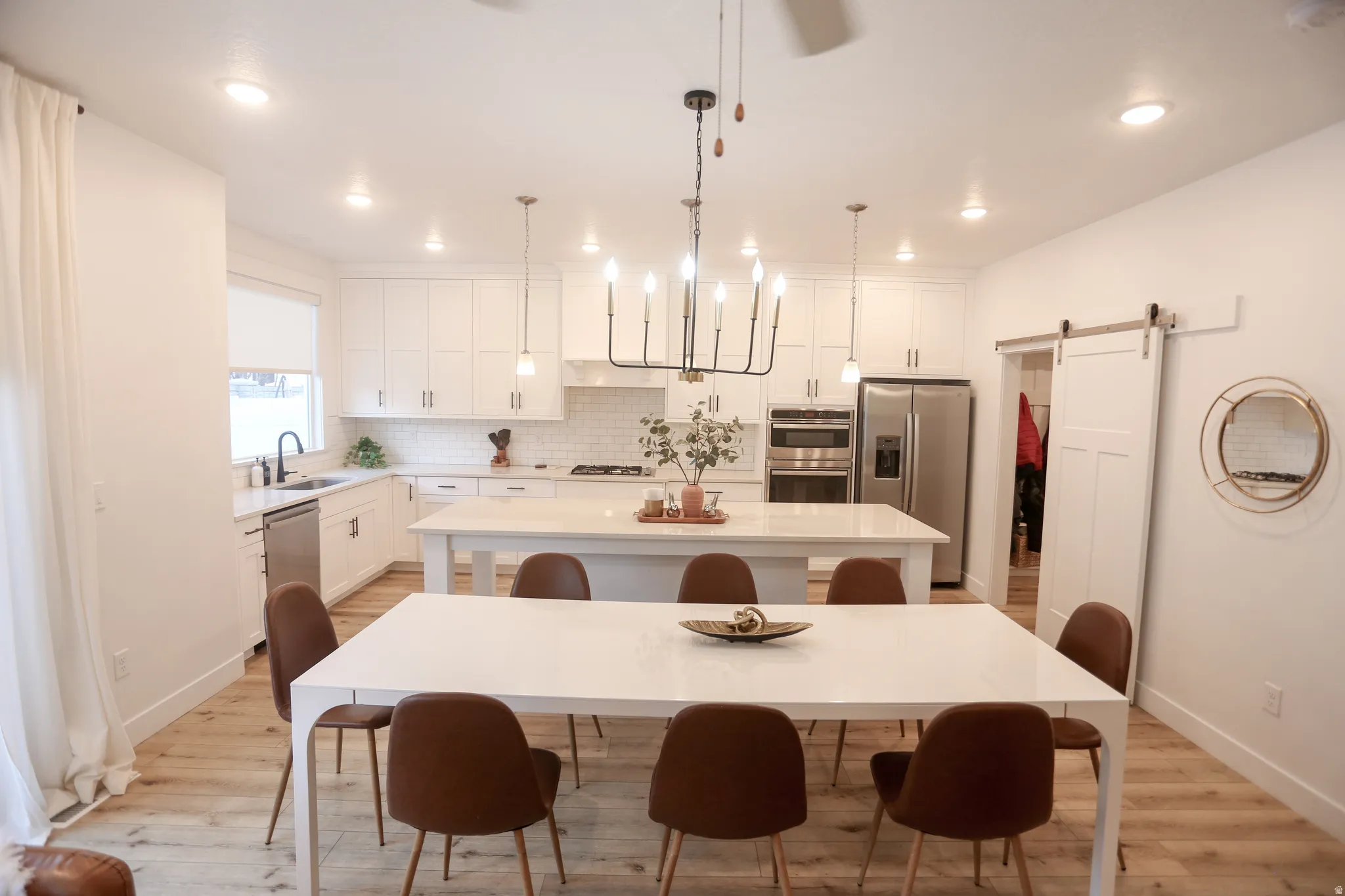 Dining room featuring a barn door, light wood-style floors, and recessed lighting