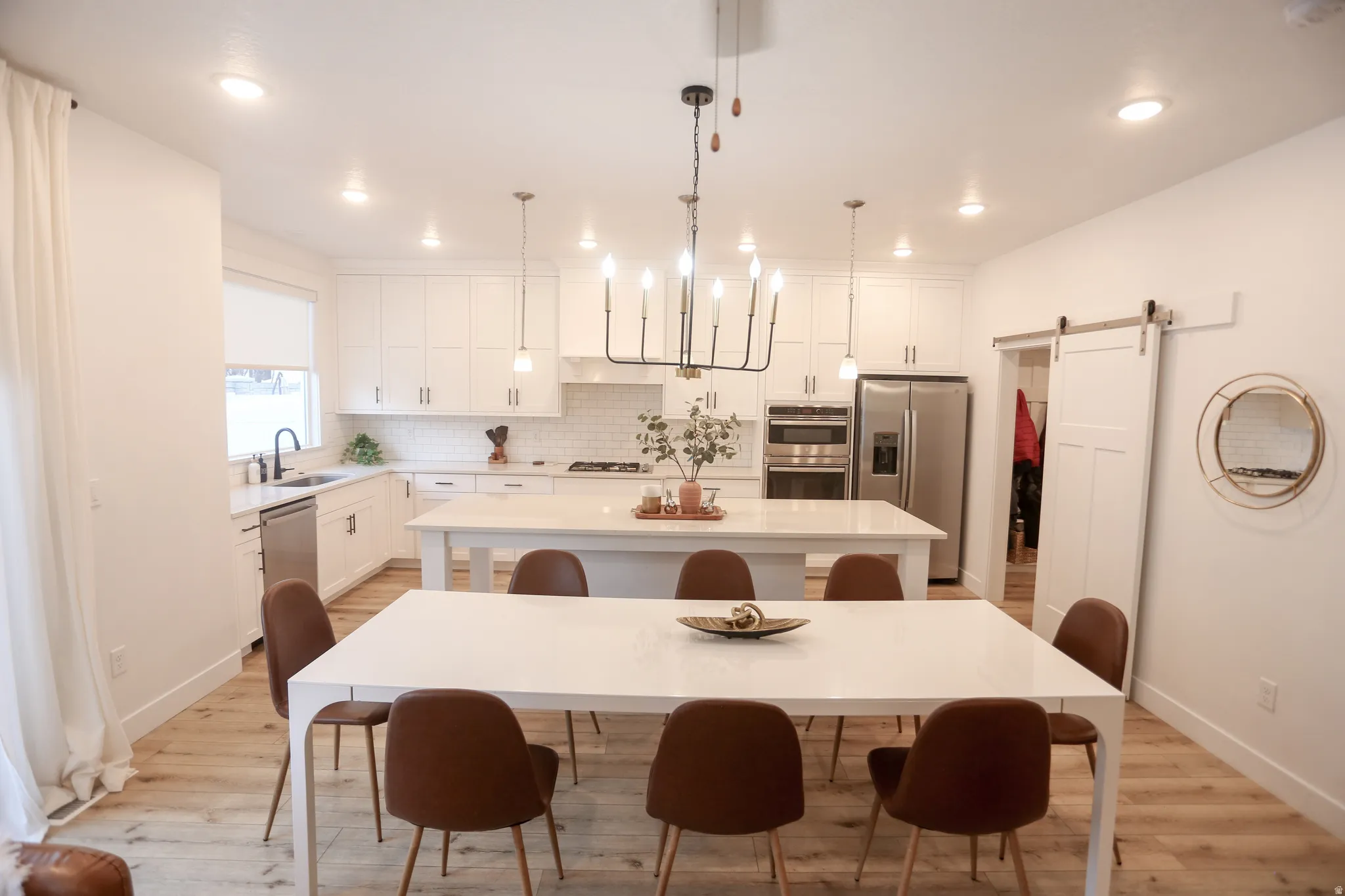 Dining space with a barn door, light wood-style floors, and recessed lighting