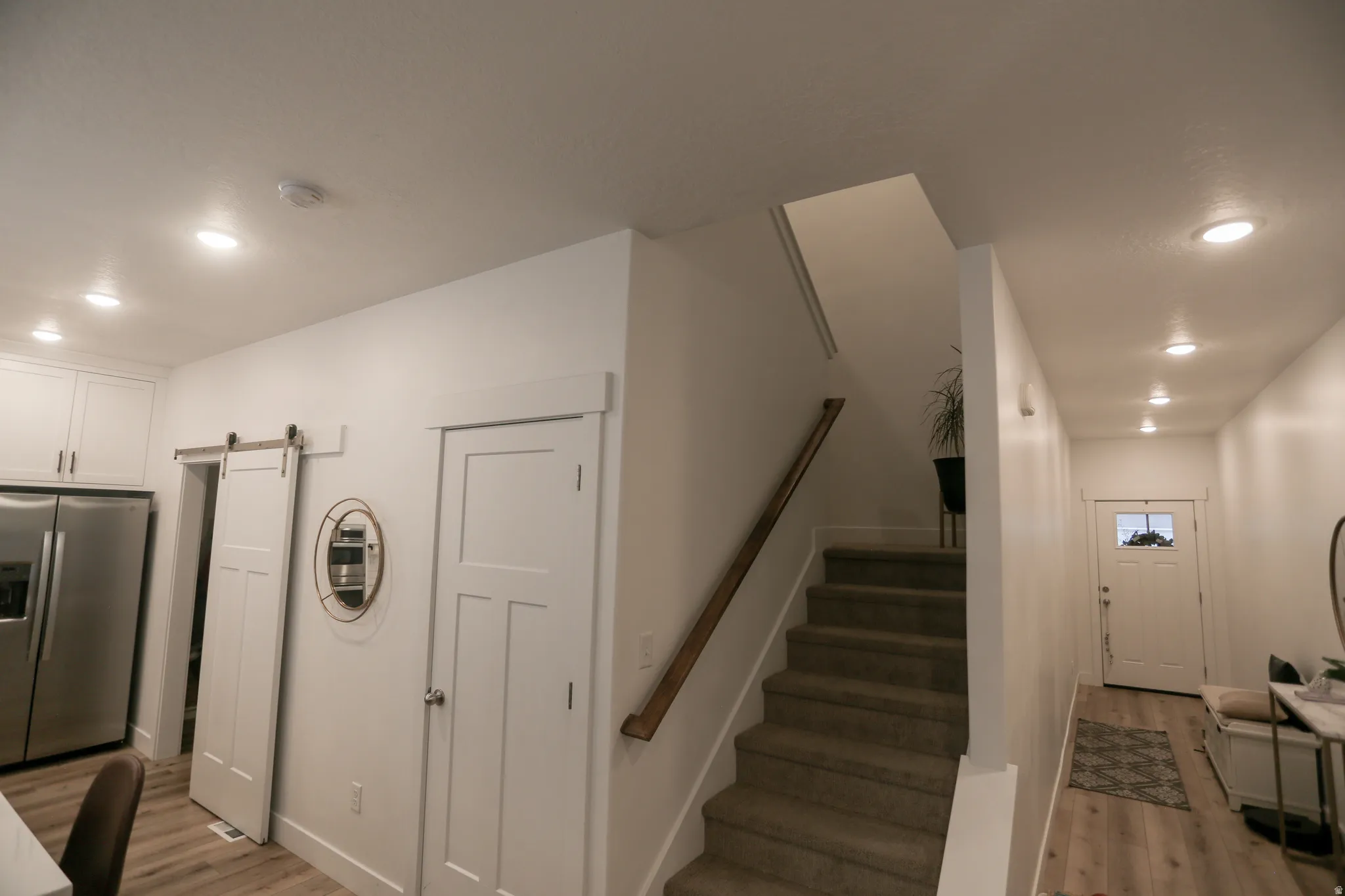 Stairway featuring recessed lighting, a barn door, and wood finished floors