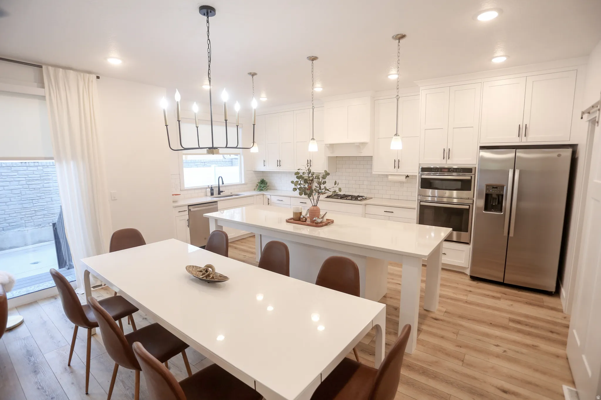 Kitchen featuring stainless steel appliances, white cabinetry, a kitchen island, a breakfast bar, and light wood-style floors