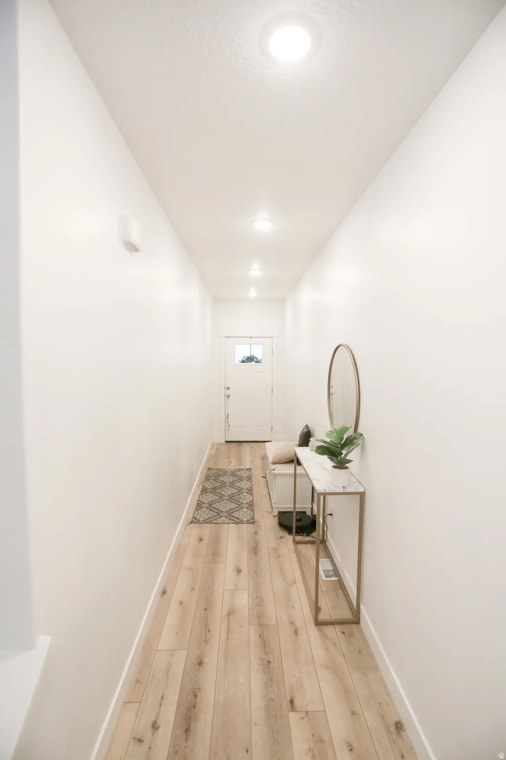 Hallway featuring light wood finished floors and baseboards