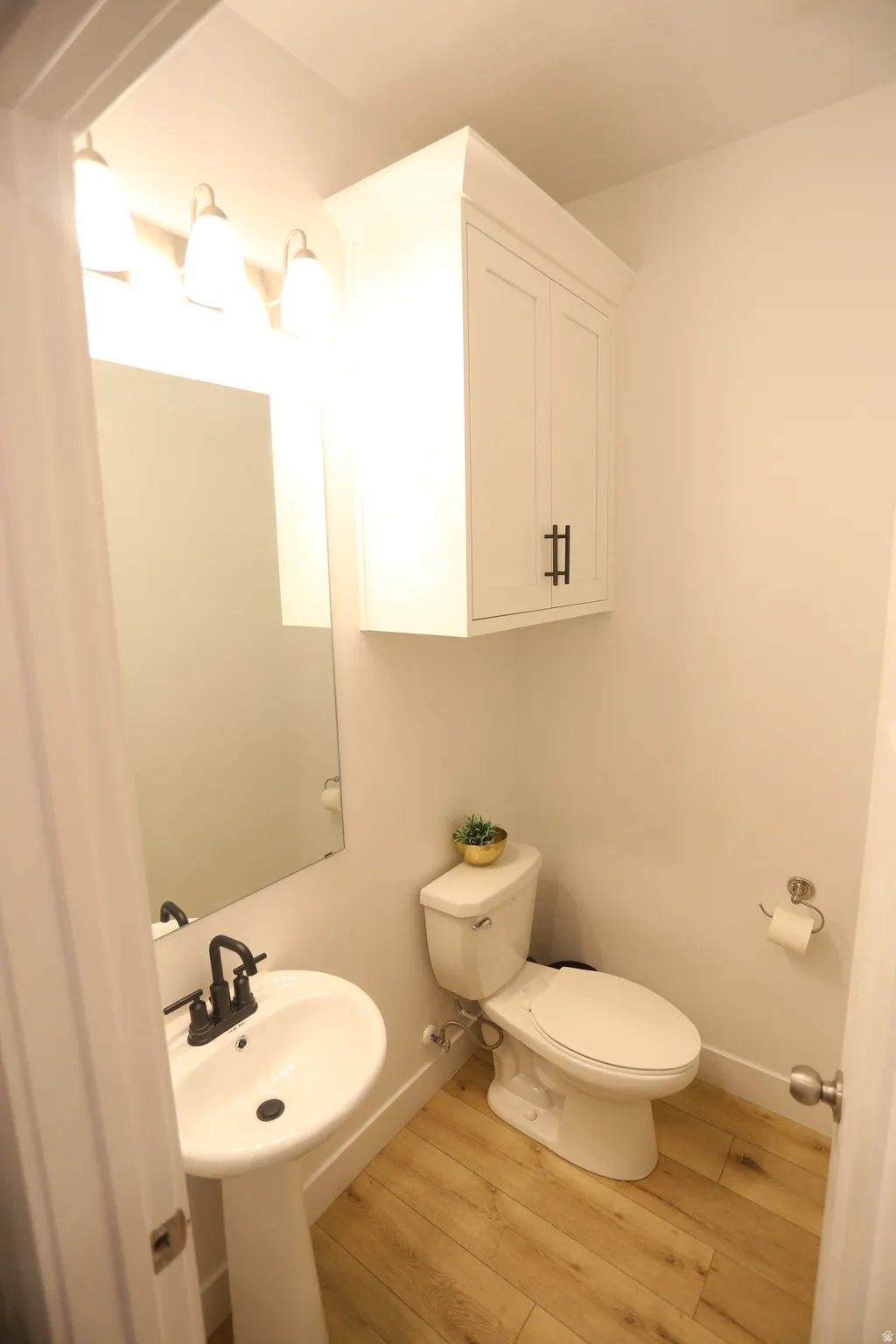 Half bathroom with light wood-type flooring and toilet